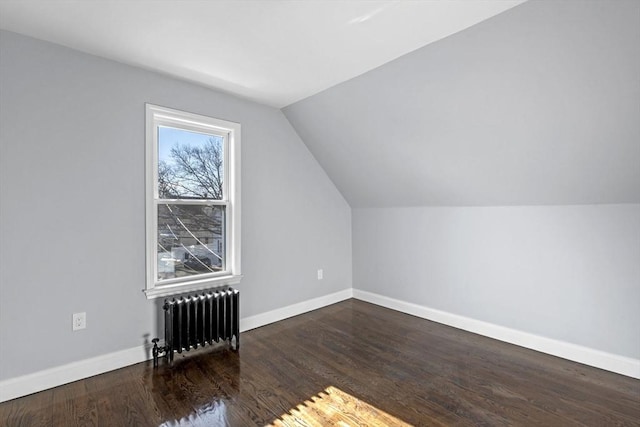 additional living space with radiator heating unit, vaulted ceiling, and dark hardwood / wood-style floors