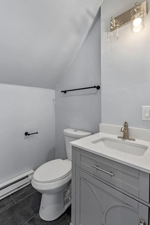 bathroom featuring toilet, tile patterned flooring, lofted ceiling, a baseboard heating unit, and vanity