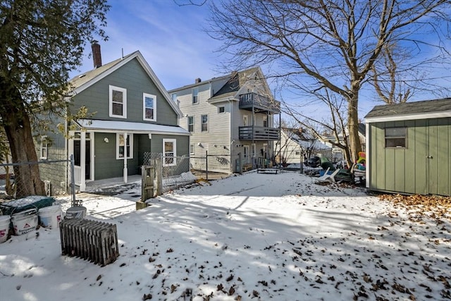 snow covered rear of property with a storage shed