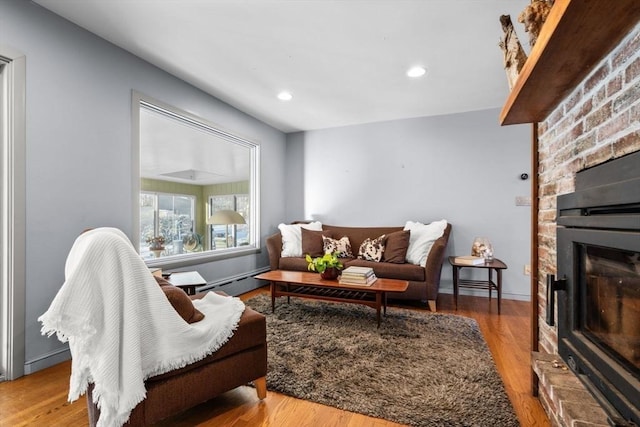 living room with a fireplace, light hardwood / wood-style floors, and a baseboard heating unit