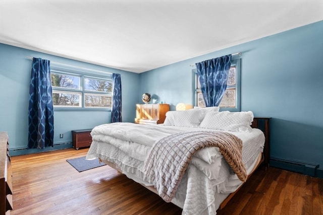 bedroom featuring a baseboard heating unit and hardwood / wood-style floors