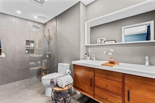 bathroom with vanity, tiled shower, tile patterned floors, and toilet