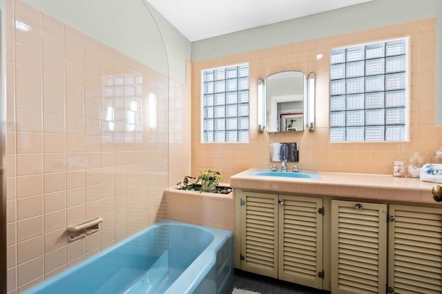 bathroom with vanity, a bath, tasteful backsplash, and tile walls