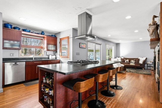 kitchen featuring a kitchen island, appliances with stainless steel finishes, a breakfast bar area, island exhaust hood, and light hardwood / wood-style floors