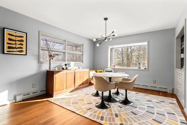 dining area with a baseboard heating unit, hardwood / wood-style flooring, and a chandelier