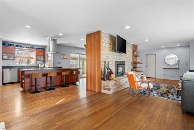 living room with a wealth of natural light, a stone fireplace, and light wood-type flooring