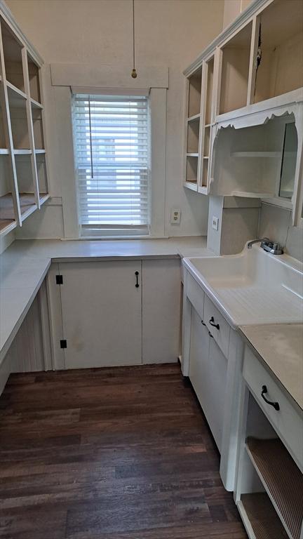 kitchen with dark wood-type flooring, white cabinetry, and sink