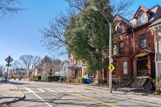view of road featuring curbs, traffic signs, sidewalks, and a residential view