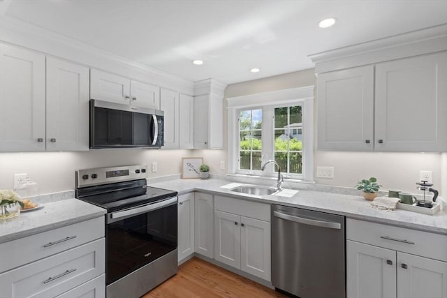 7 Grove St, Westford, MA 01886 - kitchen with stainless steel appliances, a sink, white cabinets, light wood-type flooring, and light stone countertops