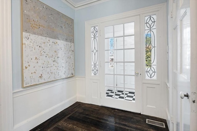 foyer entrance with a wainscoted wall, visible vents, dark wood finished floors, and crown molding