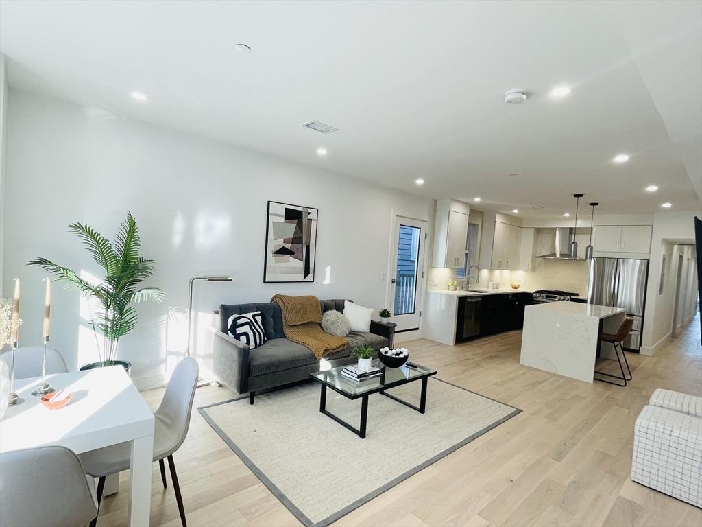 kitchen with white cabinets, plenty of natural light, wall chimney range hood, and appliances with stainless steel finishes