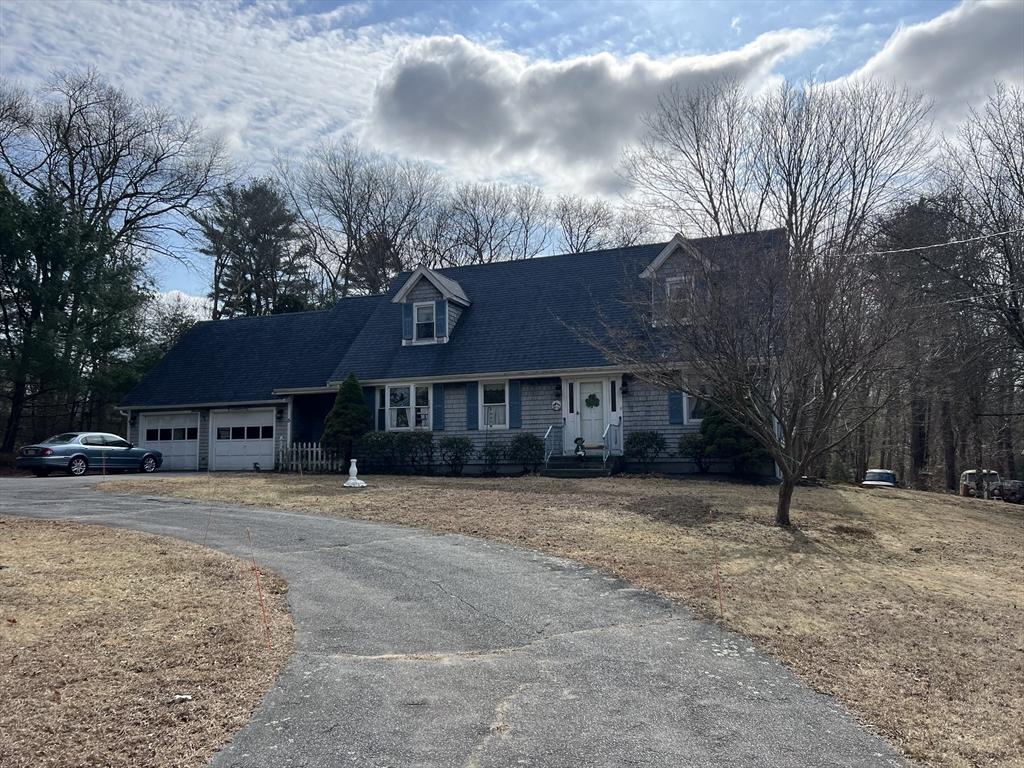 new england style home with aphalt driveway, an attached garage, and a shingled roof