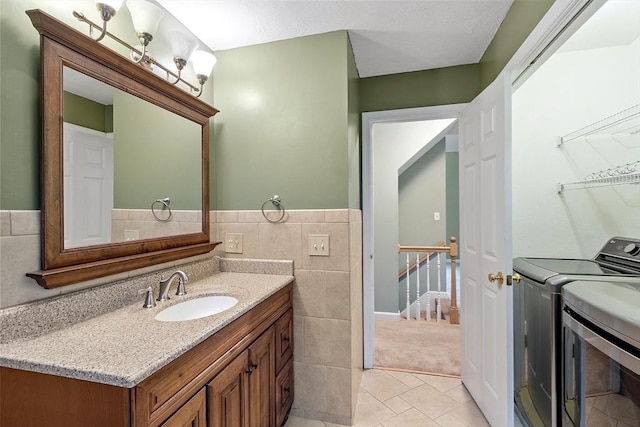 93 Towne Hill Rd, Haverhill, MA 01835 - bathroom featuring separate washer and dryer, tile patterned floors, tile walls, vanity, and a wainscoted wall