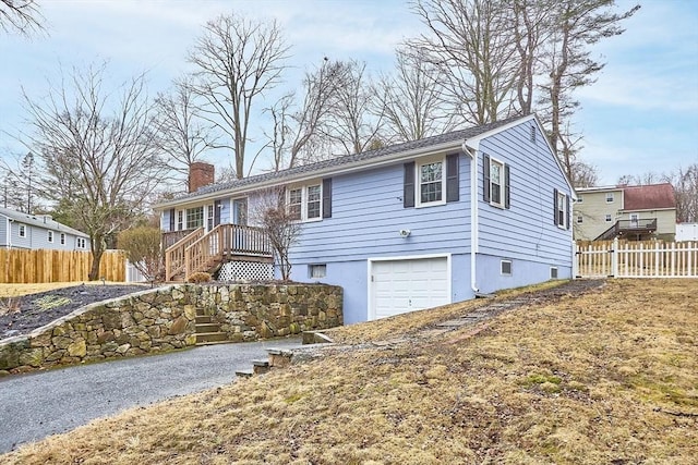 ranch-style home with a garage, a chimney, and fence