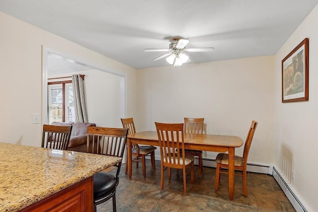 dining room featuring ceiling fan, baseboard heating, and stone finish flooring