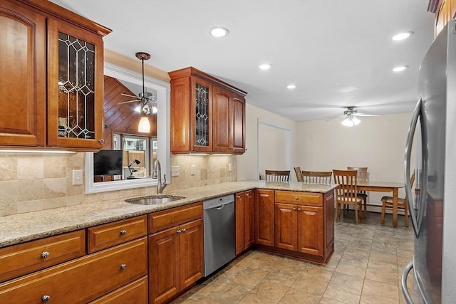 kitchen featuring brown cabinets, a ceiling fan, a sink, stainless steel appliances, and a peninsula