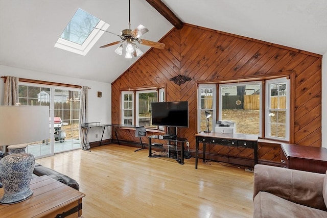 living area with wooden walls, ceiling fan, beamed ceiling, wood finished floors, and high vaulted ceiling