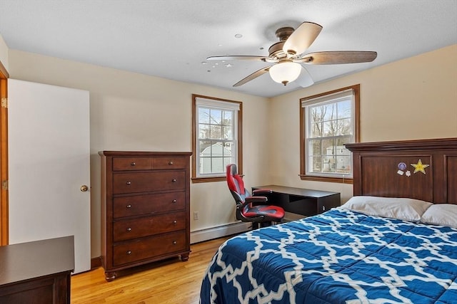 bedroom with a ceiling fan, light wood-style floors, and a baseboard radiator