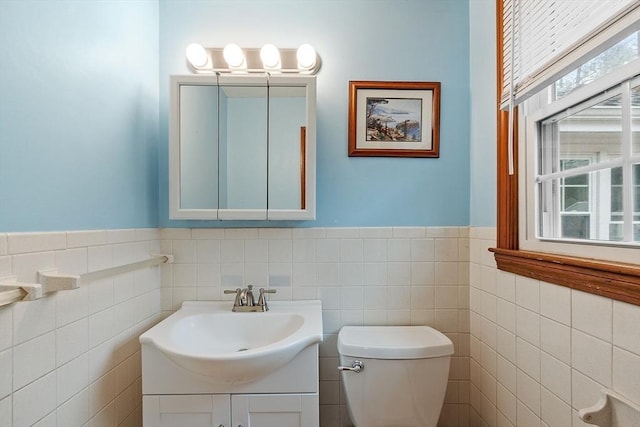 half bathroom featuring tile walls, plenty of natural light, toilet, and vanity