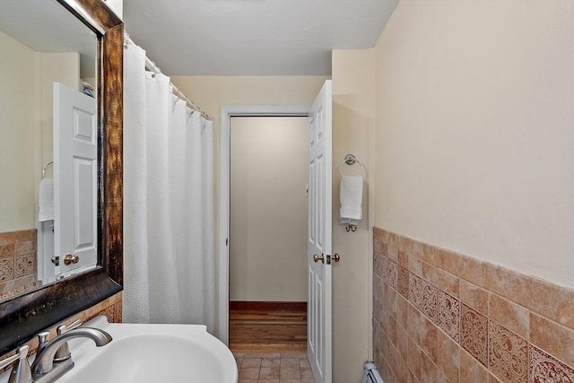 bathroom with a shower with shower curtain, tile walls, and a sink