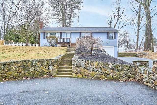 view of front of home featuring aphalt driveway, fence, stairway, an attached garage, and a chimney