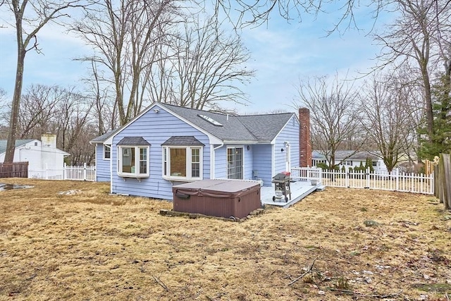 exterior space featuring a shingled roof, a fenced backyard, a chimney, and a hot tub