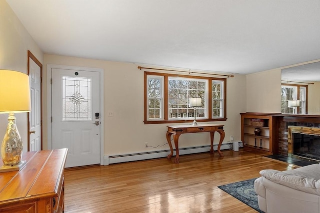 living area with light wood-style flooring, a brick fireplace, and a baseboard radiator