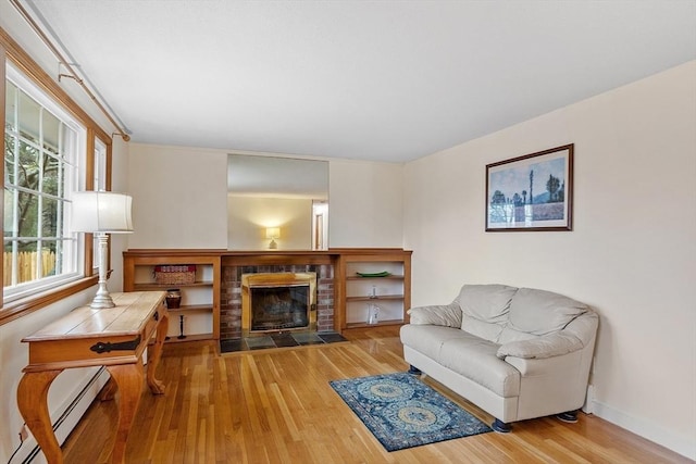 living room featuring a fireplace, wood finished floors, baseboards, and baseboard heating