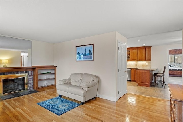 living area with recessed lighting, light wood-type flooring, baseboards, and a glass covered fireplace