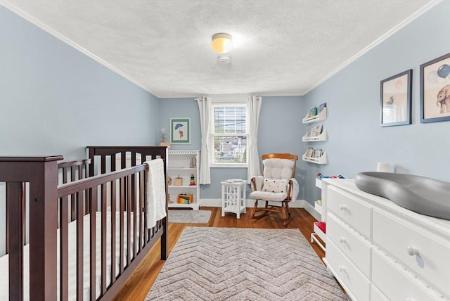 571 Washington St, Winchester, MA 01890 - bedroom featuring ornamental molding, a textured ceiling, a nursery area, wood finished floors, and baseboards