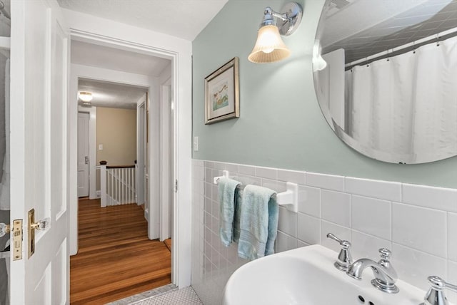 571 Washington St, Winchester, MA 01890 - bathroom featuring a sink, tile walls, wood finished floors, and a wainscoted wall