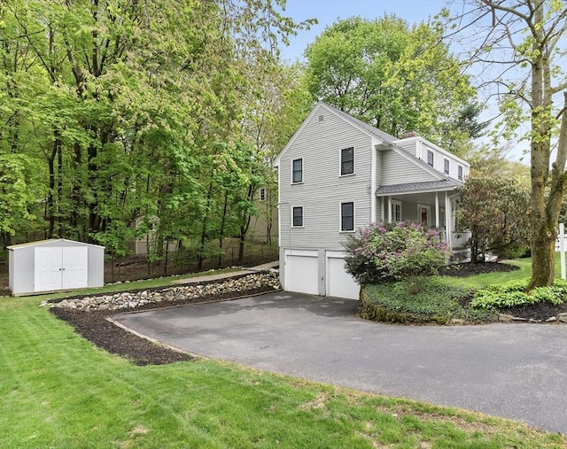 571 Washington St, Winchester, MA 01890 - view of home's exterior with asphalt driveway, a garage, a storage shed, a yard, and an outdoor structure