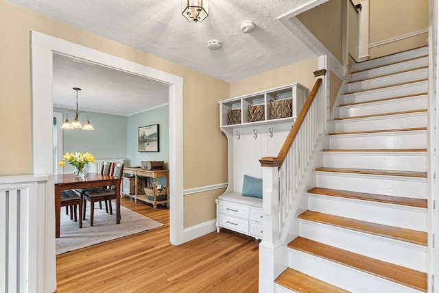 571 Washington St, Winchester, MA 01890 - staircase with wood finished floors, a chandelier, a textured ceiling, and crown molding