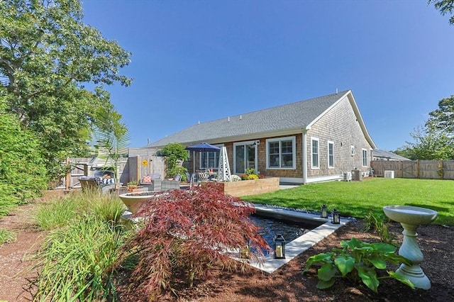 back of property featuring a fenced backyard, a vegetable garden, and a yard