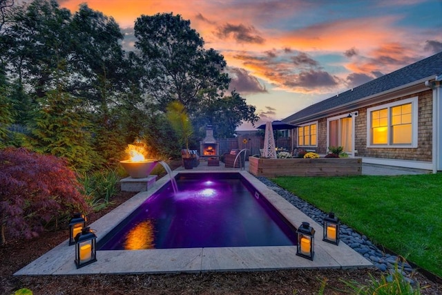 pool at dusk with a fire pit, an outdoor pool, a lawn, fence, and a patio area