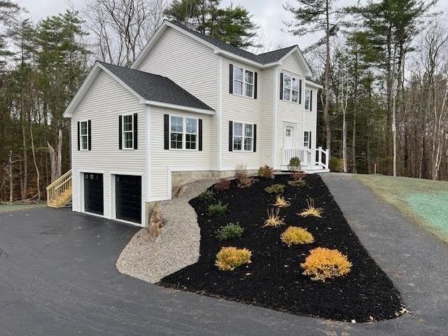 colonial inspired home with a garage and aphalt driveway