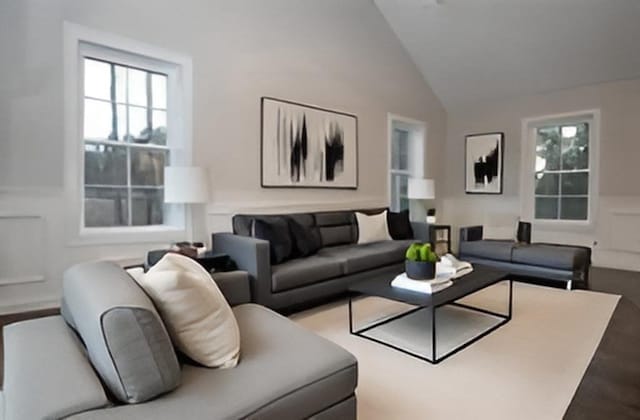 living room featuring plenty of natural light, wainscoting, high vaulted ceiling, and a decorative wall