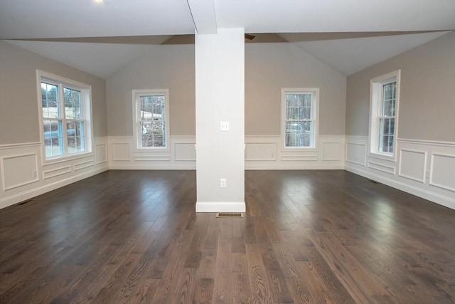 unfurnished room featuring dark wood finished floors, vaulted ceiling, and visible vents