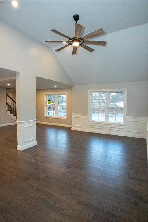 unfurnished living room with stairway, a wealth of natural light, a decorative wall, and ceiling fan