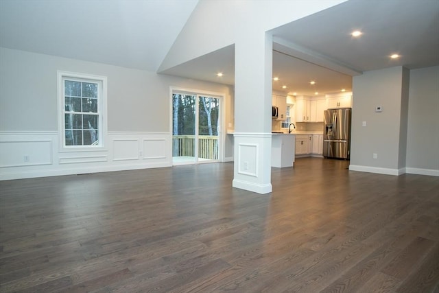 unfurnished living room with dark wood-style floors, lofted ceiling, recessed lighting, and a sink