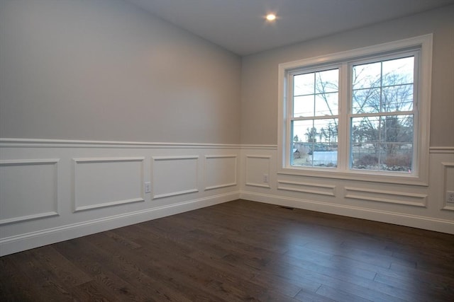empty room featuring dark wood finished floors and wainscoting
