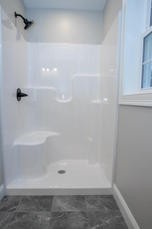 full bathroom featuring marble finish floor, baseboards, and a walk in shower