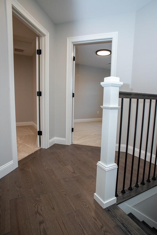 hallway with an upstairs landing, baseboards, and wood finished floors
