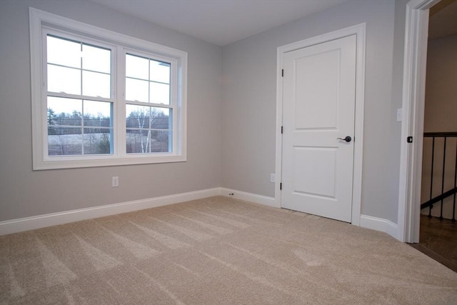 unfurnished room with light carpet and baseboards