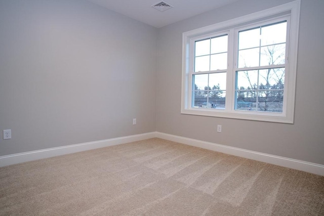 spare room with baseboards, visible vents, and light carpet