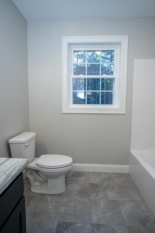 full bathroom with toilet, vanity, a bathtub, marble finish floor, and baseboards