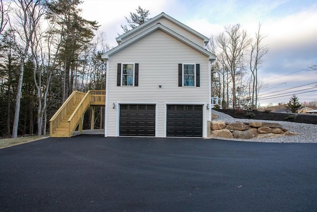view of home's exterior with driveway, a garage, and stairway
