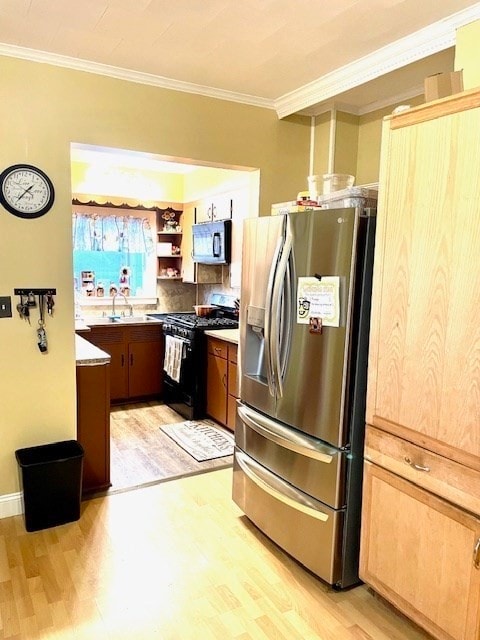 kitchen featuring appliances with stainless steel finishes, sink, crown molding, and light hardwood / wood-style flooring