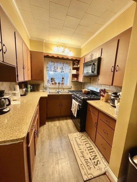 kitchen featuring light wood-type flooring, sink, black appliances, and ornamental molding