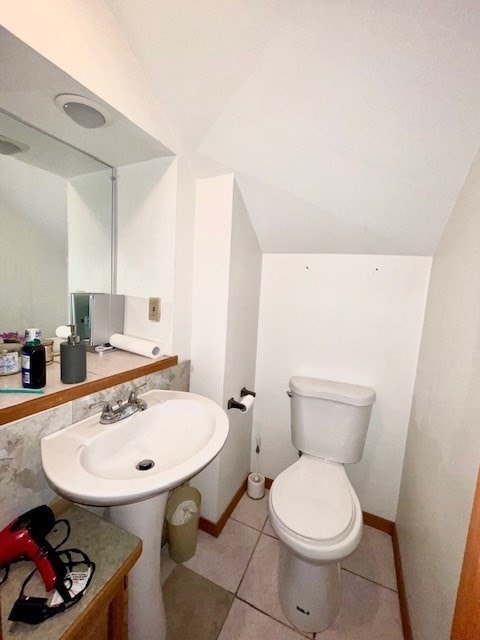 bathroom with toilet, lofted ceiling, and tile patterned flooring